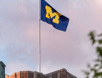 University of Michigan logo flag flying in the wind