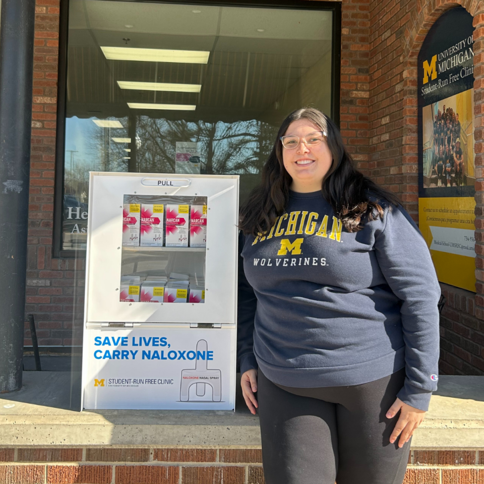 PharmD Student Nicole Long poses for a photo next to a Naloxone box at the Student Run Free Clinic. 