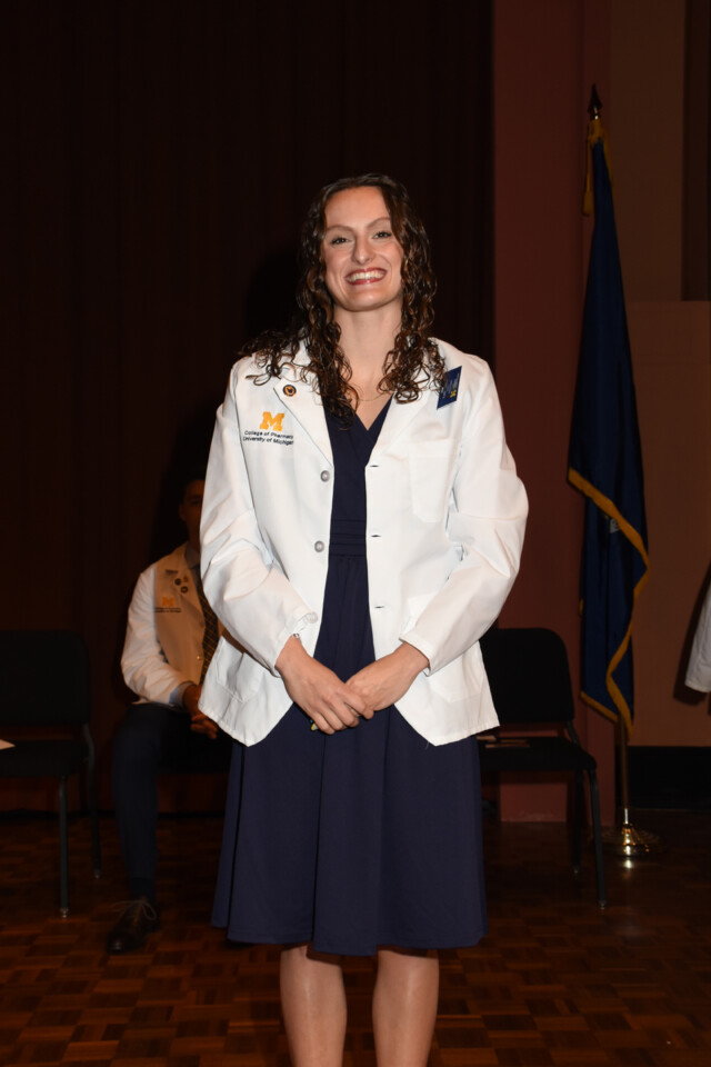 Female posing for a photo wearing her College of Pharmacy White Coat
