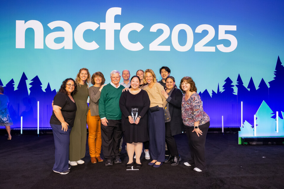Group of people at NACFC conference with a woman in the middle holding an award