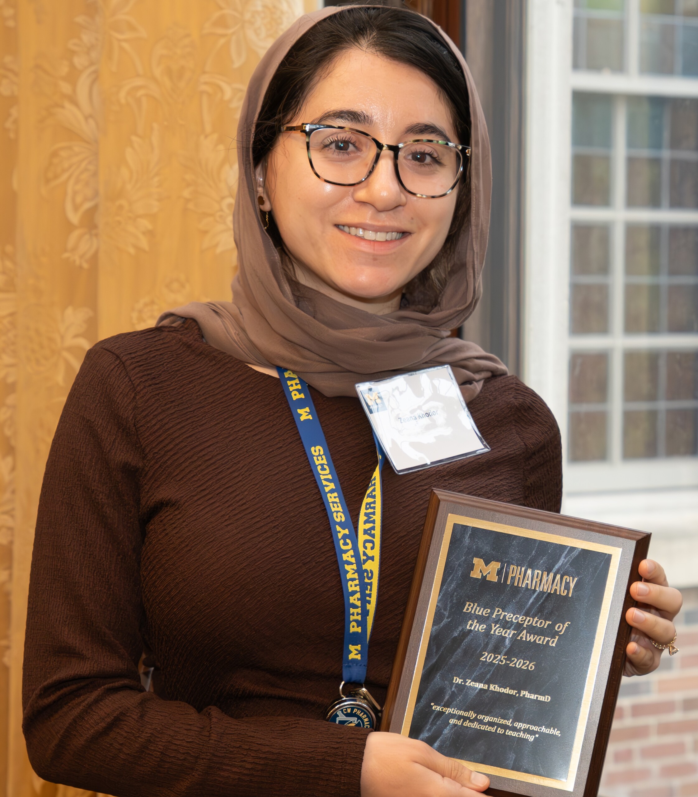 Dr. Zeana Khodor is smiling with the Blue Preceptor of the Year Award.