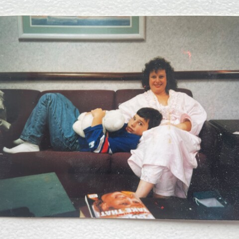 Dan Hertz as a child lying on a couch with his mother.