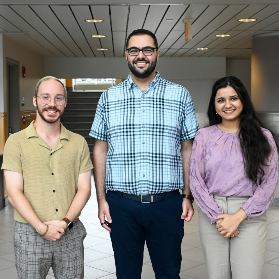 Two men and one woman pose for a photo in business casual clothing