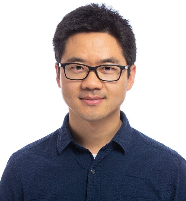 Julian Zhu poses in front of a white background