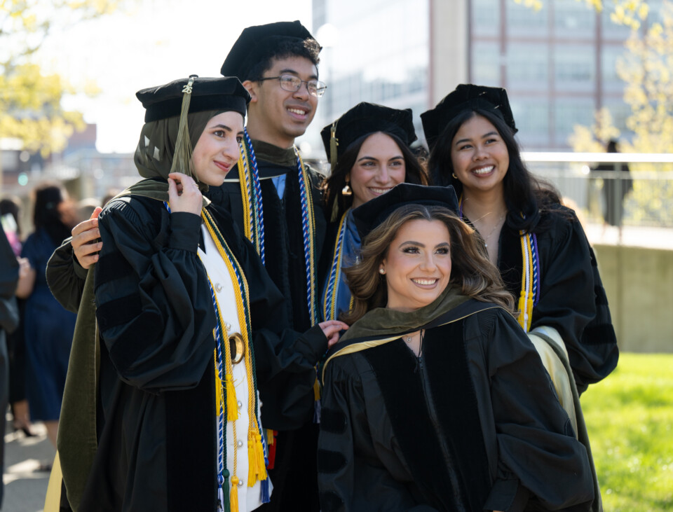2026 Graduates of the College of Pharmacy smiling for a group photos in the academic attire