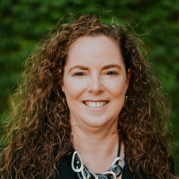 Curly haired woman standing in front of a green background