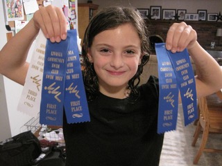 Child holding up ribbons she won from swimming
